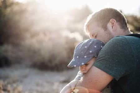 Père tenant tendrement son enfant dans les bras, illustrant le lien familial au cœur des tests de paternité